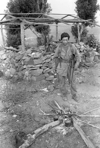 A Salvadoran Army soldier stands in front of small fire at an outpost, Perquín, 1983