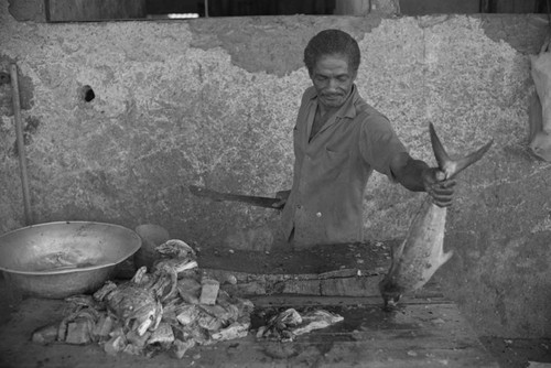 Man cleaning fish at city market, Cartagena Province, ca. 1978