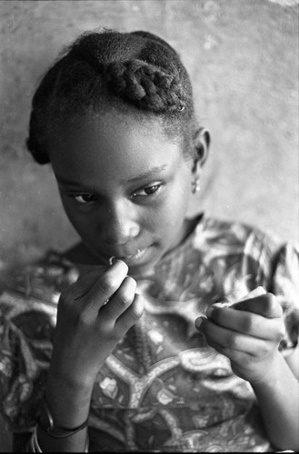 Girl threading a needle to sew a garment, San Basilio de Palenque, 1977