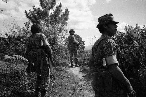 Armed soldiers walk idle on a country road, Guatemala, 1982