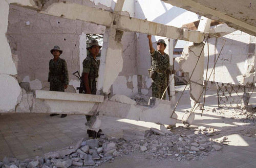 Soldiers stand near destroyed building, Guatemala, 1982