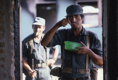 A young Contra soldier eats from a green plastic bowl, Nicaragua, 1983