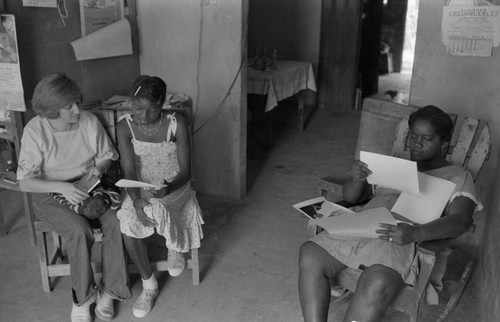 Nina S. de Friedemann and a woman looking at pictures, San Basilio del Palenque, ca. 1978