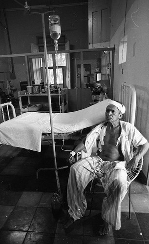 Man with IV sitting near a hospital bed, Nicaragua, 1979