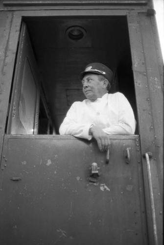 Railway porter peers out window of sleeping car, Chihuahua 1983