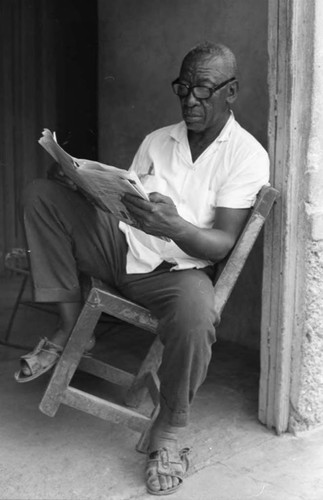 Fermín Herrera reading the newspaper, San Basilio de Palenque, 1975