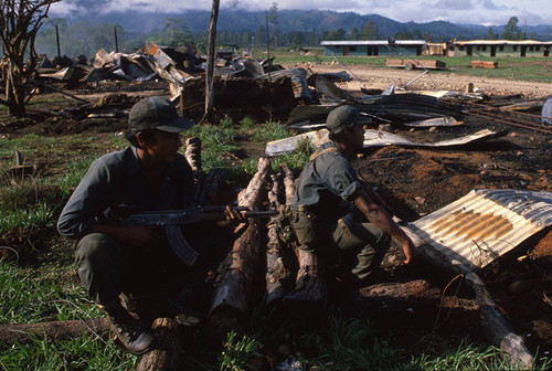 Two Contra soldiers sit on a fallen trunk, Nicaragua, 1983