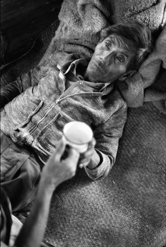 Refugee man lies on a reed mat and blankets, Chiapas, 1983