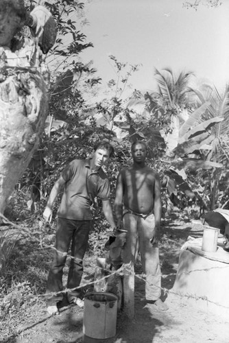 Richard Cross and a man standing in front of a hand pump, San Basilio de Palenque, ca. 1978