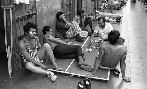 Men sitting outside cells in prison, Nicaragua, 1980