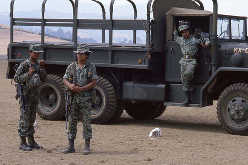 Three soldiers hang around a truck at military base, Santa Cruz del Quiché, 1982