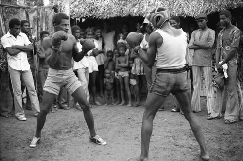 Two men boxing outdoor in front of crowd, San Basilio de Palenque, 1975