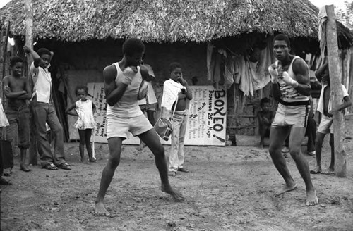 Two men boxing outdoor in front of a crowd, San Basilio de Palenque, 1975