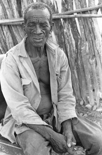 Man sitting with joined hands, San Basilio de Palenque, 1975