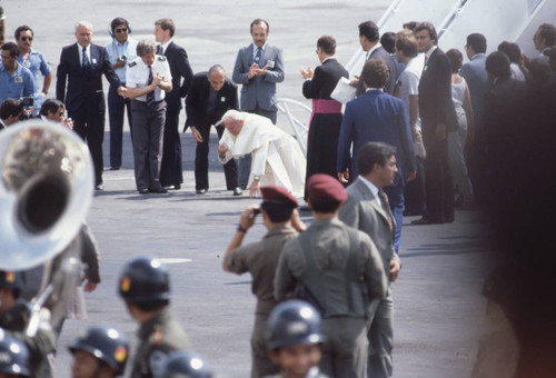 Pope John Paul II kneeling on his arrival, San Salvador, El Salvador, 1983