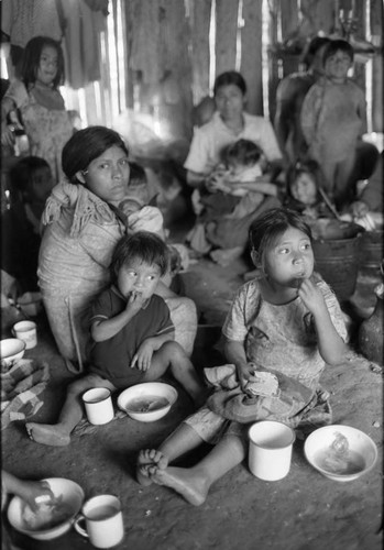 Refugee women and children gather in a hut to eat, Chiapas, 1983