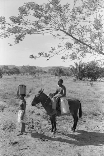 Woman and man carrying metal containers, San Basilio de Palenque, ca. 1978