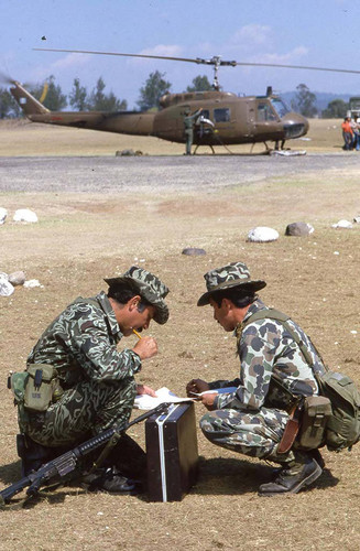 Two military officers crouch over documents at the military base, Santa Cruz del Quiché, 1982