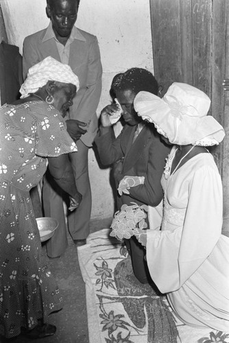 Woman standing in front of kneeling wedding couple, San Basilio del Palenque, ca. 1978