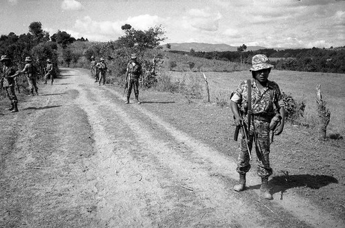 Armed soldiers stand on a road, Guatemala, 1982