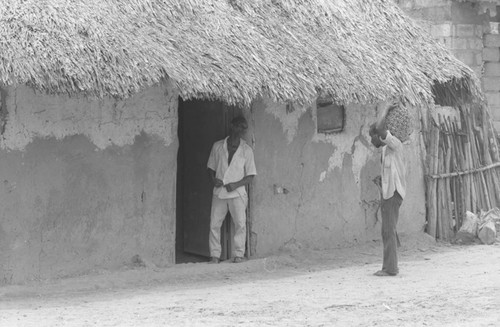 Two men talking in front of a house, San Basilio de Palenque, 1976