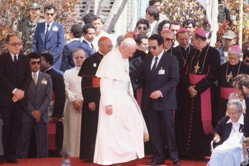 Pope John Paul II standing among clergy and officials, San Salvador, El Salvador, 1983