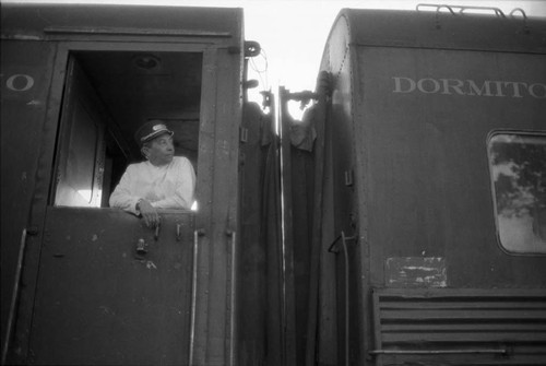 Railway porter peers out window of sleeping car, Chihuahua 1983