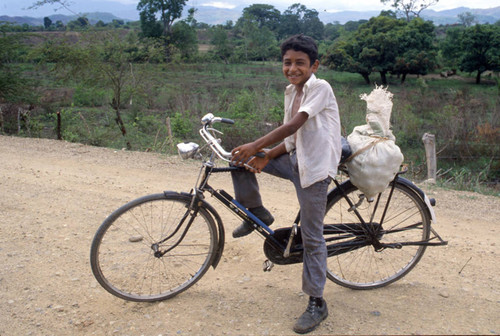 Boy on a bicycle smiling, Honduras, 1983