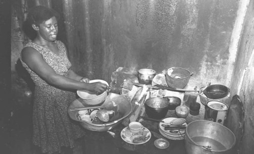 Woman washes dishes inside a house, San Basilio de Palenque, 1975