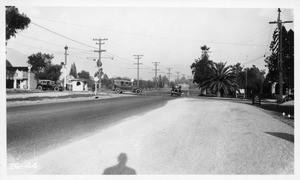 Looking east on Huntington Drive from west side of Rose Avenue, showing south roadway of Huntington Drive narrowed down east of Rose Avenue and palm tree on southeast corner which obstructs vision, Los Angeles County, 1926