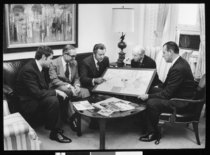 Herbert G. Klein and staff examining a map of world destinations