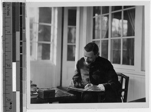 Priest writing in a book, Japan, ca. 1900-1920