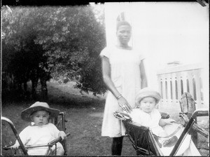 African nanny with toddlers in a baby-carriage, Tanzania, ca. 1925-1930