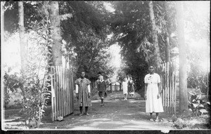 Wilhelm Blumer and six African men at the entrance to the mission station, Arusha, Tanzania, 1928