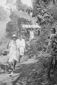 Evangelister på vandring i Kalrayan Hills, Sydindien, 1938. I disse bjerge er der kun snævre stier, så alt må bæres på hovedet. På billedet ses evangelisterne Milton (med solhat) og Sundaram i spidsen for en flok kulier på vej hjem fra turen