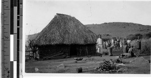 Group of people standing next to a hut, Africa, April 1947