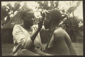 A woman having her eyebrows and the hairs on her eyelids pulled out