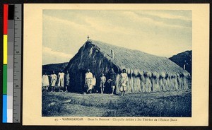 Priest and others standing before a small thatched chapel, Madagascar, ca.1920-1940