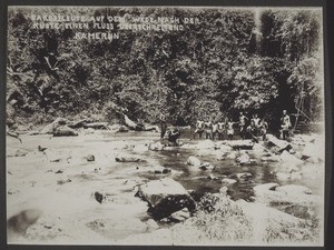 Bakosi people wading across a river on their way to the coast