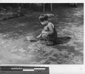 A little girl feeding a bird at Fushun, China, 1939