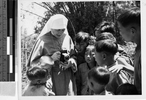 Maryknoll Sister demonstrates her camera to children, NgFa, Kaying, China, ca.1940