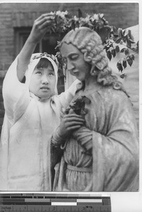 A young girl crowns a statue at Fushun, China, 1938