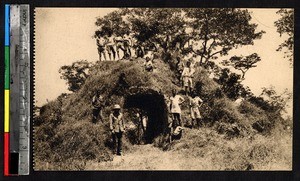 Clergy and men outside by termite mound, Kakyelo, Congo, ca.1920-1940