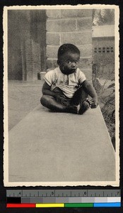 Toddler sitting by a brick pillar, Congo, ca.1920-1940