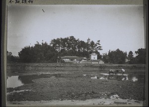 Chinese farmhouse with a threshing floor for rice surrounded by its wall and with a tower as protection from bandits