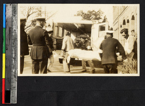 Chinese paramedics loading a patient into an ambulance, Shanghai, China, ca.1932