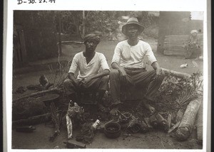 A candidate for baptism and assistent catechist Padi sitting on fetishes which have been dug out and made powerless