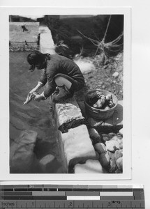 A woman washing clothes in the river in China, 1945