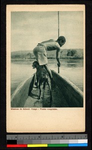 Man standing with dog at the prow of a boat, Congo, ca.1920-1940