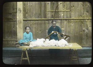 Two people working cotton on a table, China, ca.1917-1923